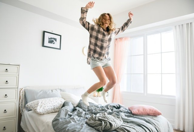 žena skákající na rozestlané posteli